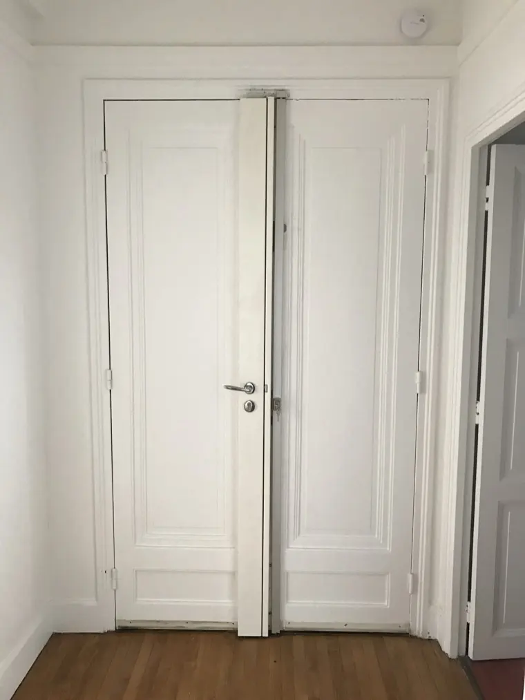 Double porte blanche renforcée, paumelles et serrure multipoints centrale visibles